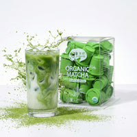 Glass of green matcha drink with a package of Organic Matcha on a white background